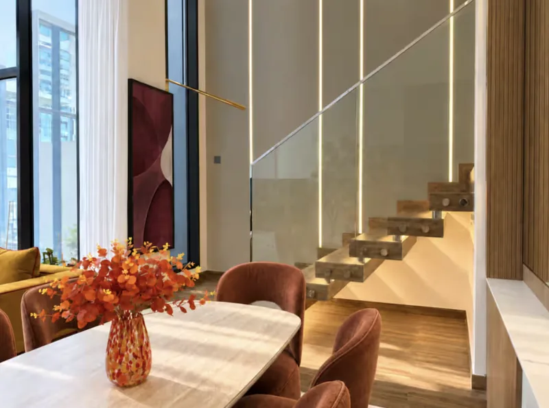 Mirage dining table with orange flowers beside the floating glass-railed staircase