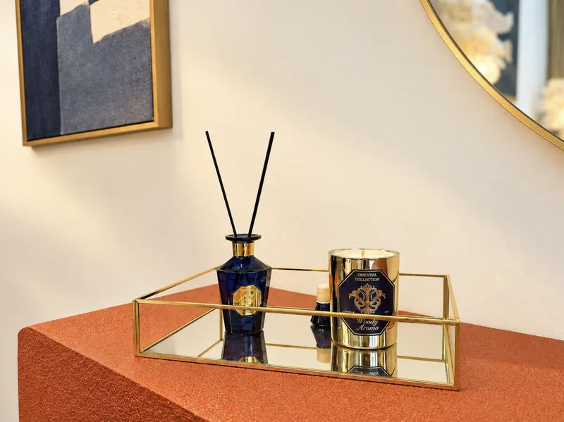 Mirrored tray with reed diffuser and gold candle on a terracotta console